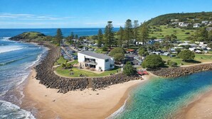 A coastal property with a white building, clear blue waters, and a rocky shoreline. - Fishers Villa (Crescent Head)