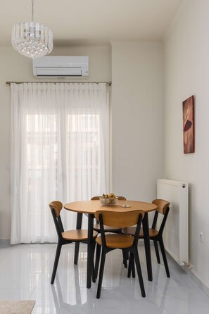 Comedor con mesa redonda, seis sillas, lámpara de araña y radiador.