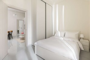 Un dormitorio moderno con una cama grande, una mesita de noche y un espejo.