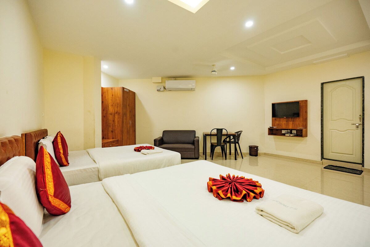 A hotel room with two beds, a TV, a wooden wardrobe, a desk, and a chair.