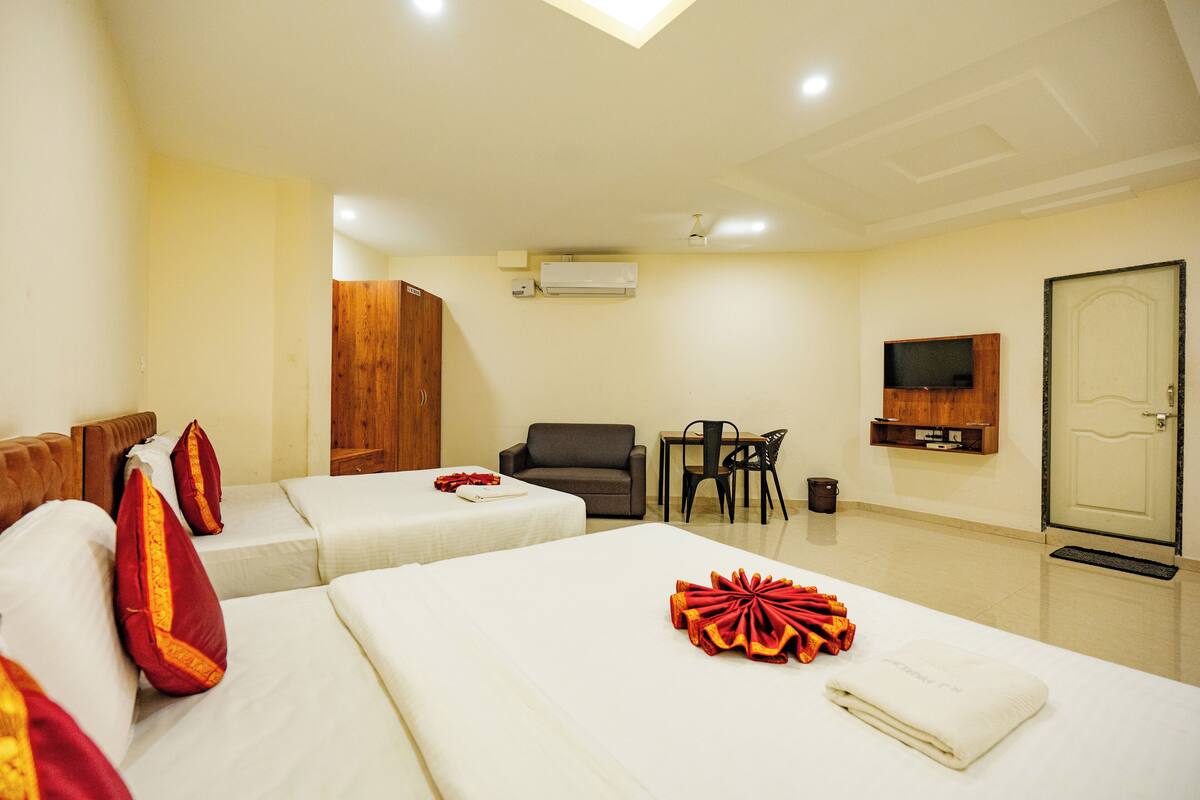 Une chambre d’hôtel avec deux lits, une télévision, un bureau et une chaise.