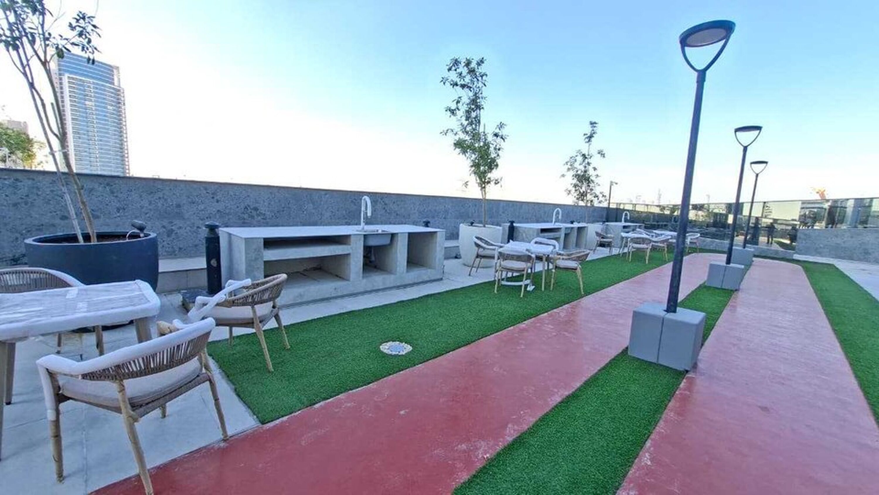 An outdoor patio with a concrete sink, seating area, and artificial grass.