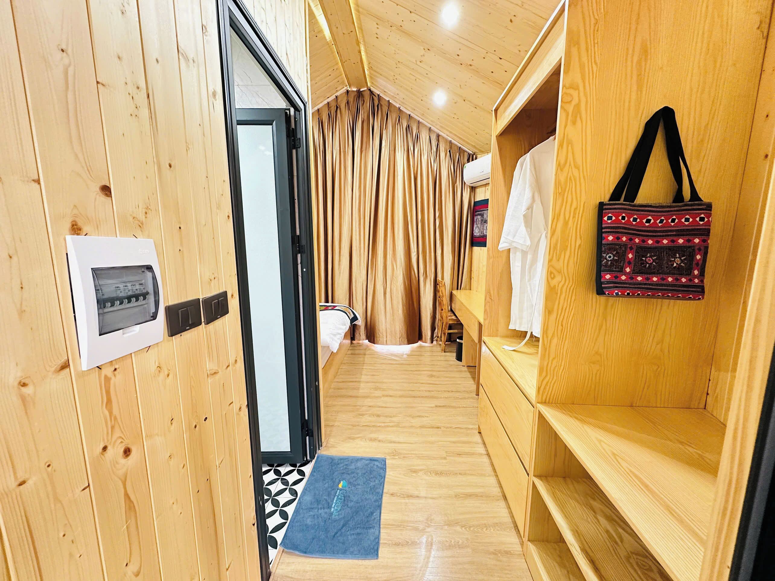 A wooden interior with a bed, a towel rack, a small bench, and a wall-mounted air conditioning unit.