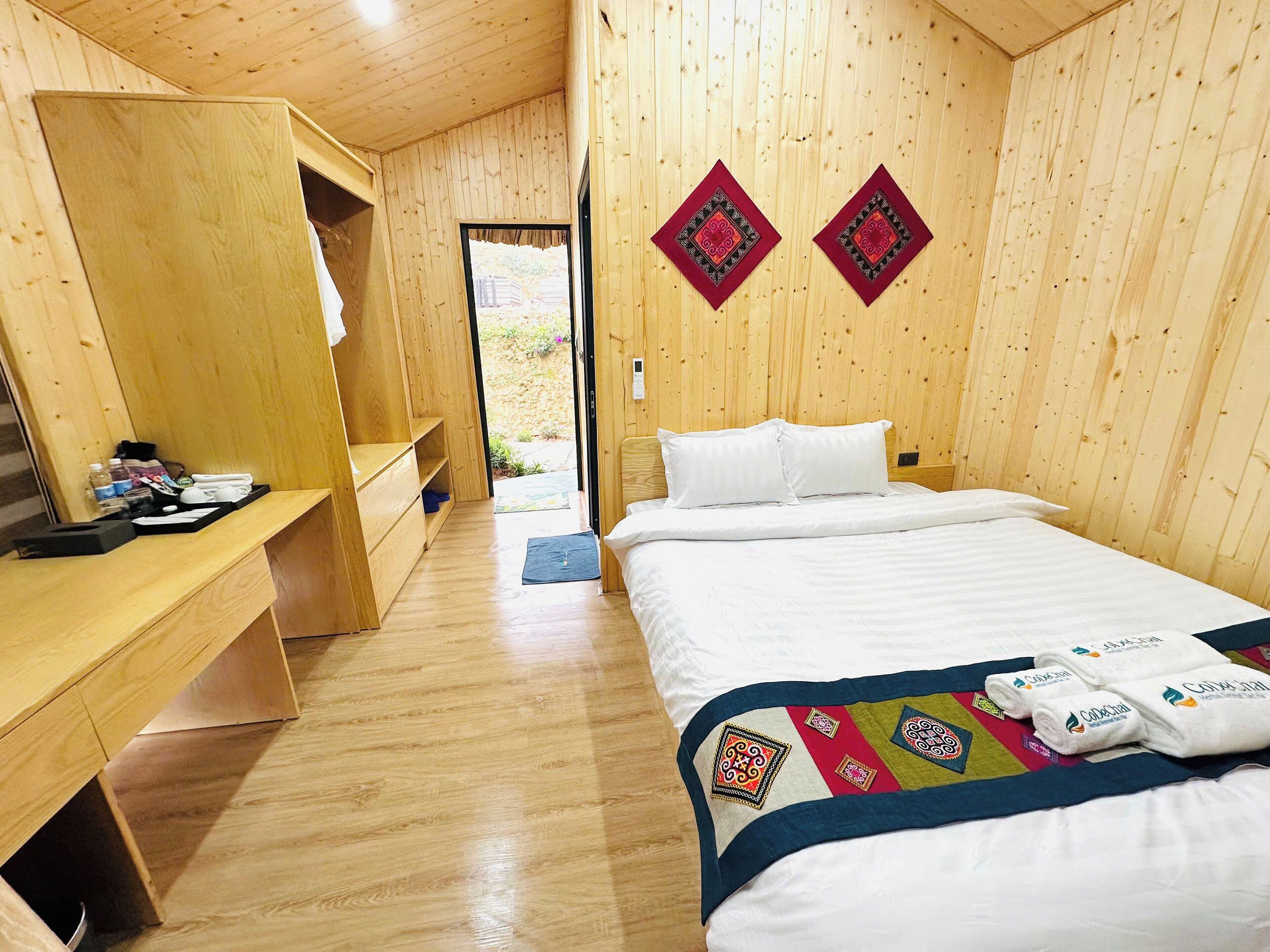 A wooden room with a bed, a desk, and a bench.