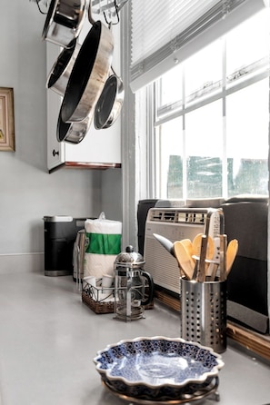 Eine Küche mit hängenden Töpfen, einer Kaffeemaschine, einem Toaster und einem Fenster mit Ausblick.