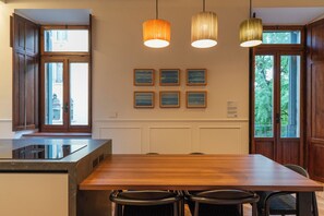 Een moderne keuken met een houten eettafel, barstoelen, hanglampen en lijstwerken aan de muur.
