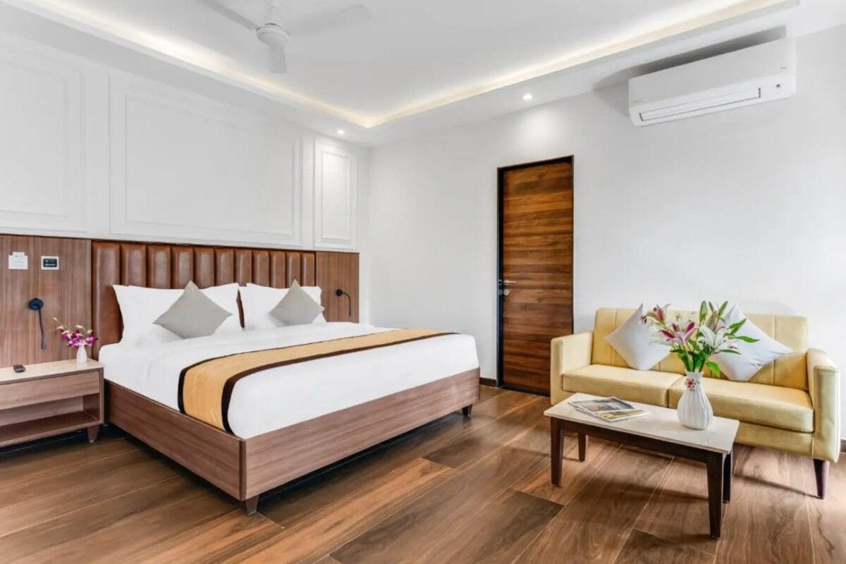 A hotel room with a wooden bed, a sofa, a coffee table, and a door.
