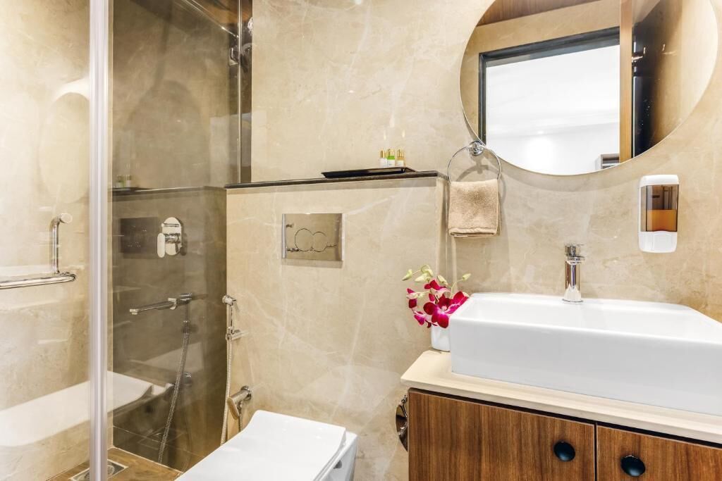 A modern bathroom with a glass-enclosed shower, a white sink, and a wooden vanity.
