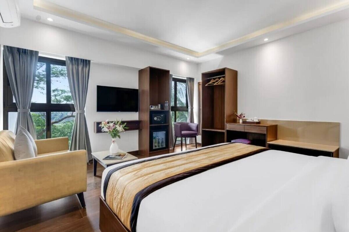 A hotel room with a bed, a desk, a chair, a TV, and a wardrobe.