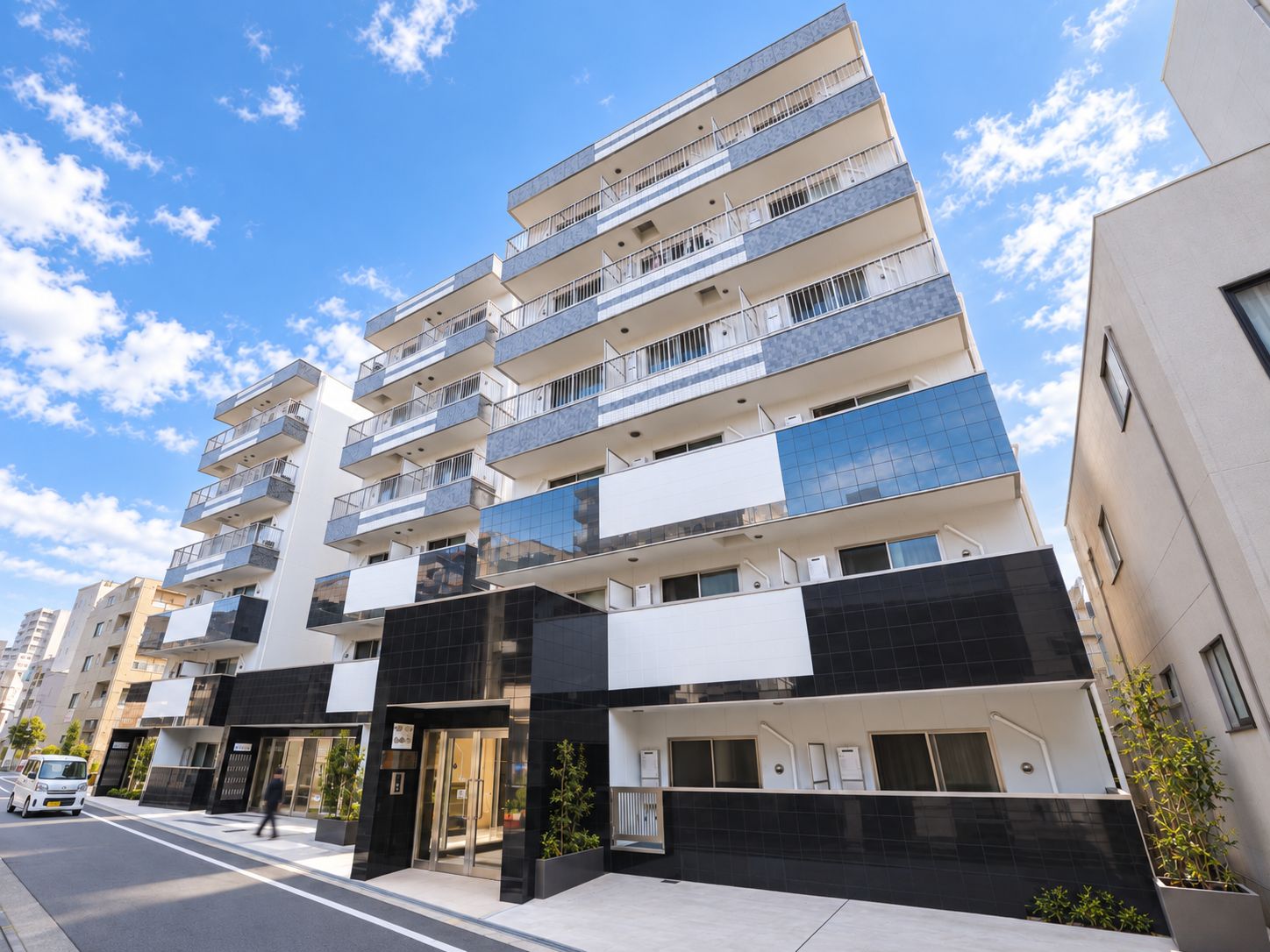 A multi-story residential building with balconies, a gated entrance, and a clear sky.