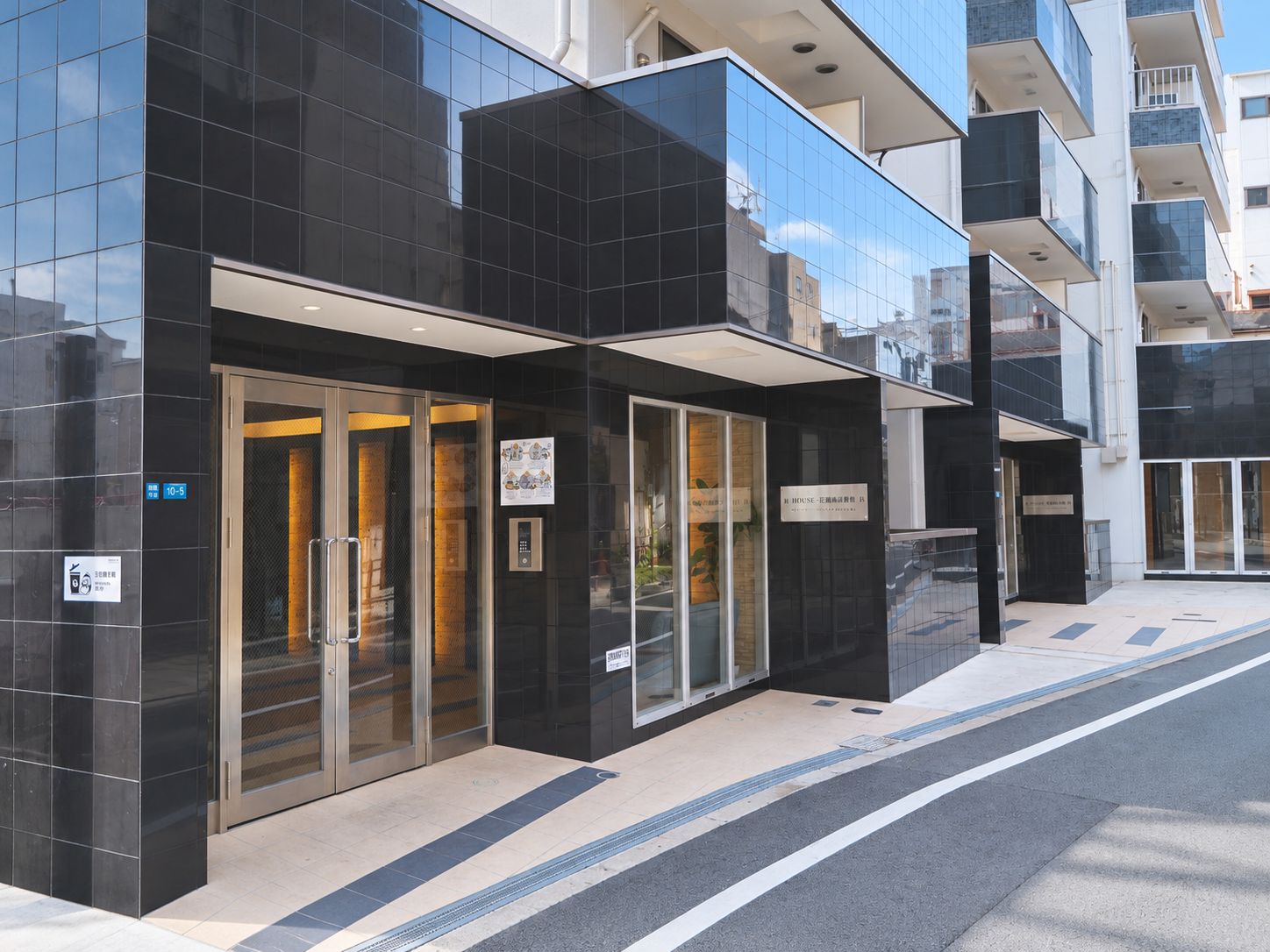 A modern building with a glass facade, a door with a sign, and a wheelchair-accessible ramp.