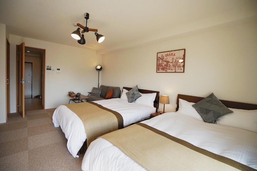 Une chambre d’hôtel avec deux lits, un bureau, une chaise, une lampe et un tableau encadré au mur.