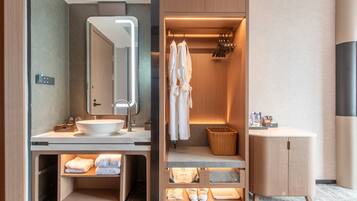 Un baño moderno con un espejo grande, dos lavamanos, un perchero para batas y una cesta.