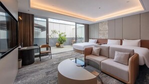 Una habitación de hotel moderna con una cama grande, un sofá, una mesita y un balcón con vistas.