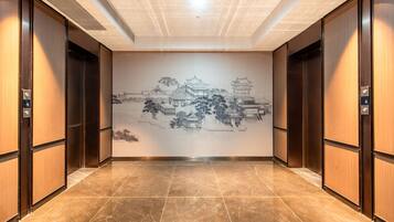 A hallway with a mural of traditional architecture, wooden doors, and a tiled floor.