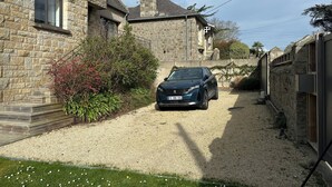 Ein Steinhäuschen mit Kiesweg und einem geparkten Auto.