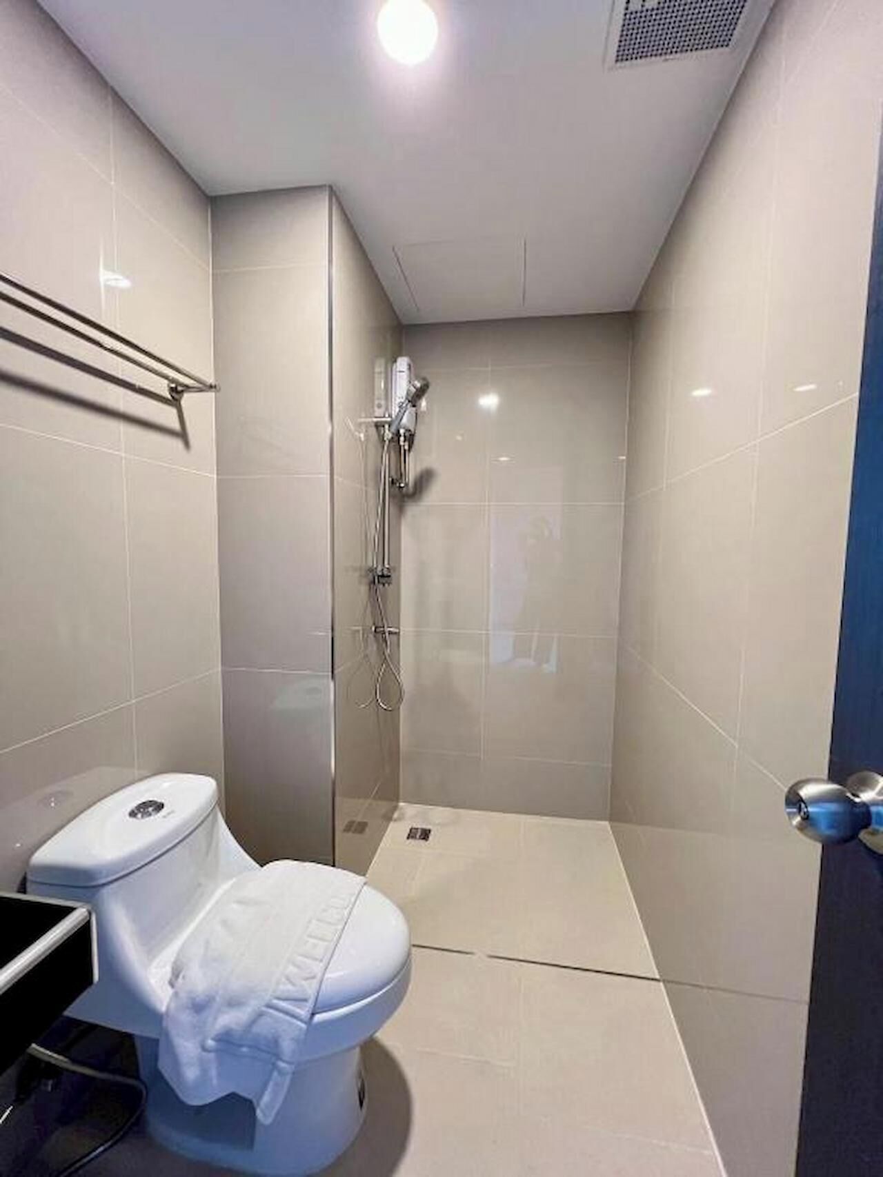A small, modern bathroom with a toilet, a shower, and a sink.