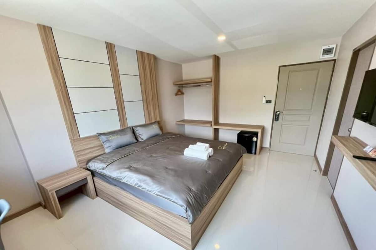 Egy modern hálószoba, amelyben egy nagy ágy, beépített polcok, egy éjjeliszekrény és egy ajtó található.