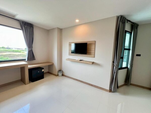 A modern room with a flat-screen TV mounted on the wall, a wooden bench, and a window with curtains. - Wellgrow Hotel at chachoengsao (Chachoengsao)