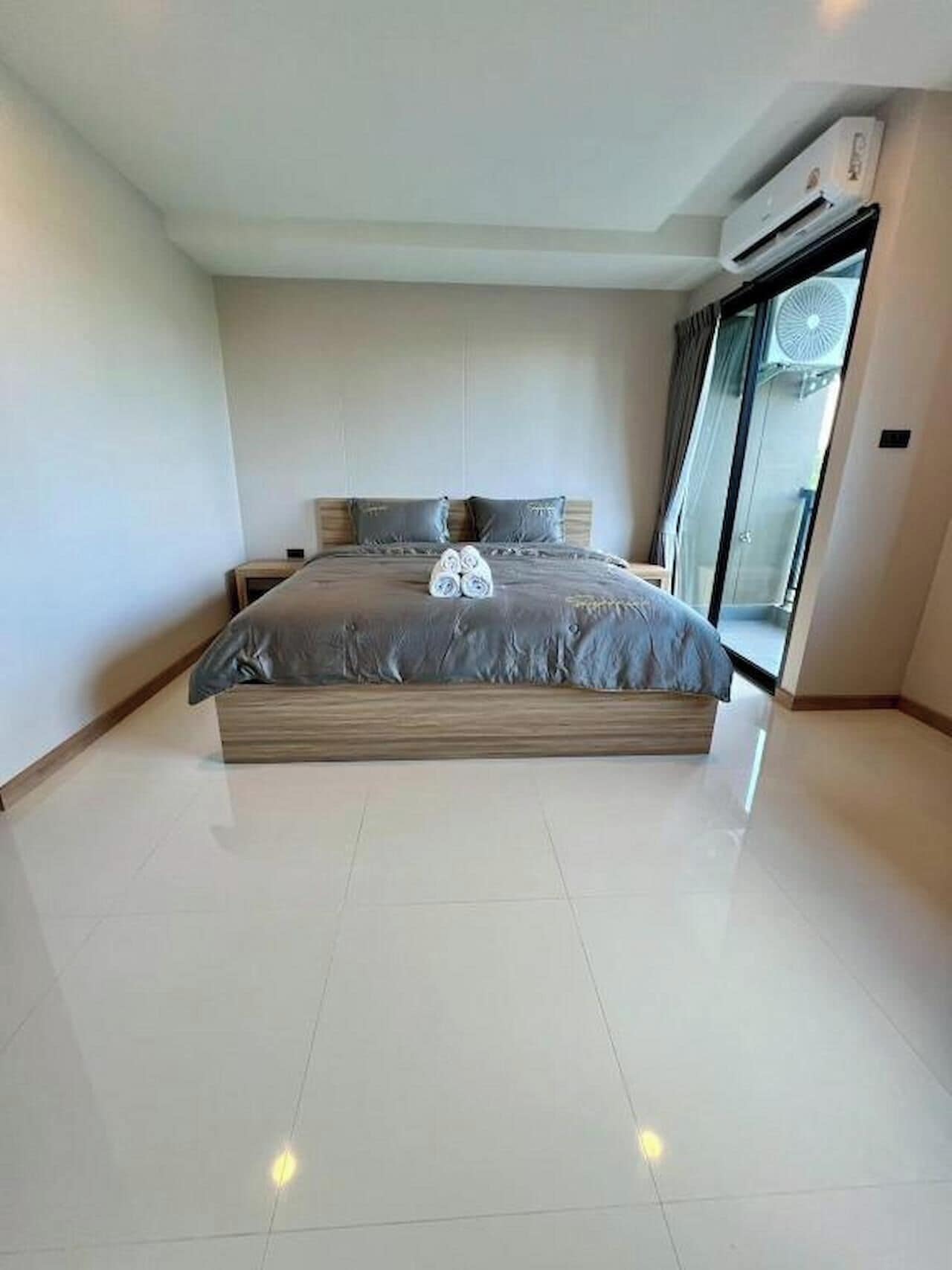 A modern bedroom with a large bed, a built-in bench, a ceiling fan, and a sliding glass door to the outside.