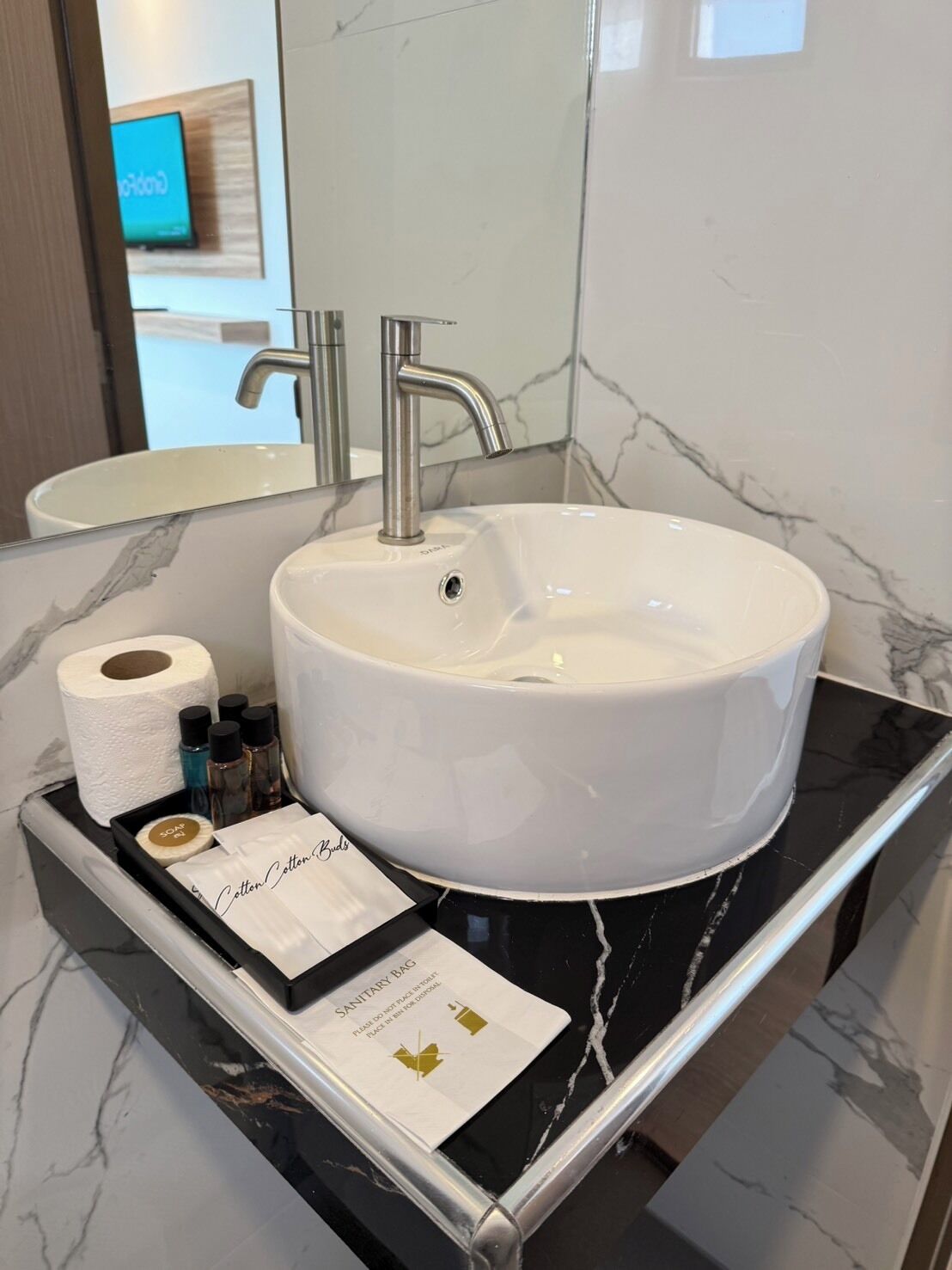 A bathroom with a white sink, a mirror, and a black countertop.