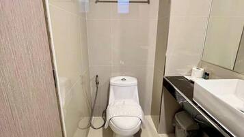 A small, modern bathroom with a toilet, bidet, and sink.