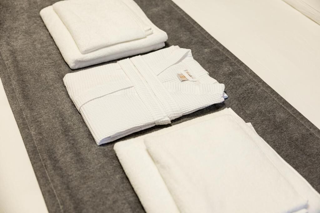 Tovalls blancs i ben plegats damunt una superfície gris, probablement a una habitació d'hotel.