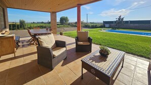 A covered patio area with outdoor furniture, a pool, and a view of the surrounding landscape.