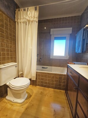 Un baño con inodoro, bañera y ventana.