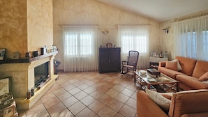 A living room with a fireplace, two windows with curtains, a wooden cabinet, and a sofa.