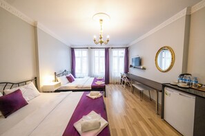 Een hotelkamer met twee bedden, een bureau, een spiegel en een kleine keukenhoek.