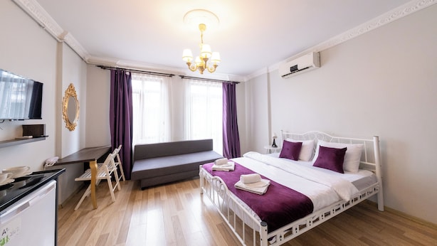 Une chambre d’hôtel moderne équipée d’un lit, d’un bureau, d’une télévision et d’une fenêtre avec des rideaux.