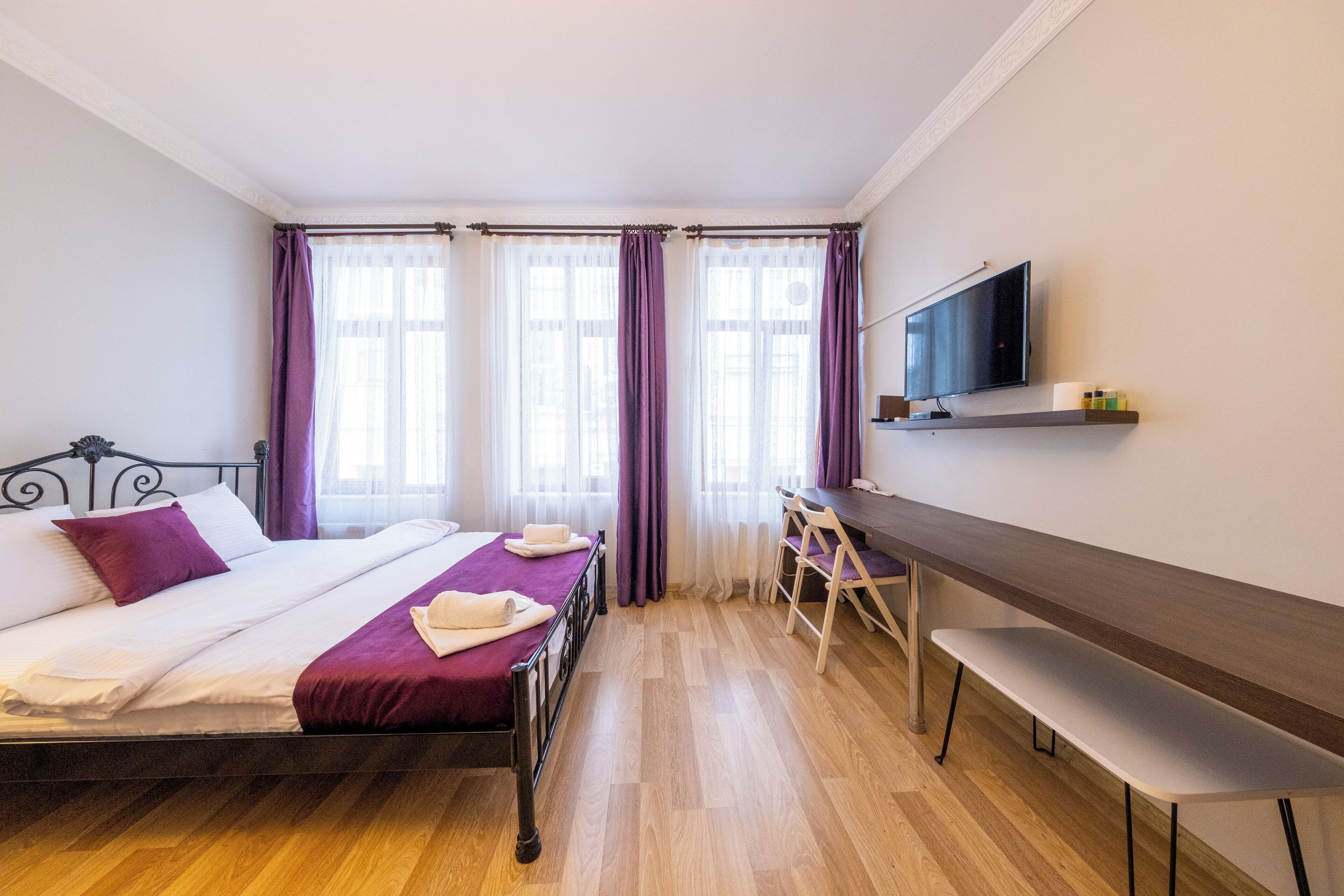 A hotel room with a bed, a desk, and a TV.