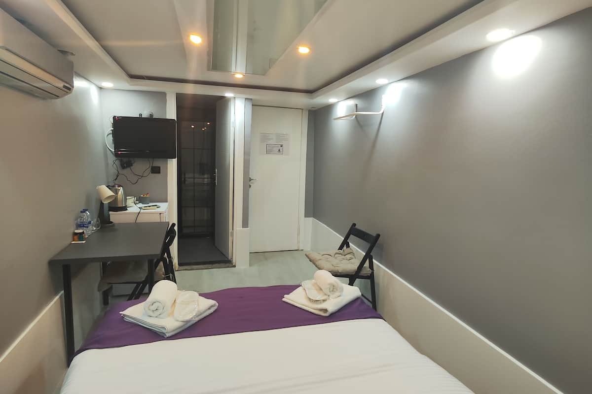 Una habitación de hotel compacta con una cama, un escritorio, una silla y un televisor.