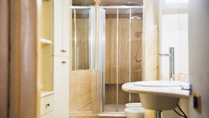 Ein modernes Badezimmer mit einer Duschkabine aus Glas, einem weißen Waschbecken und einer Toilette.