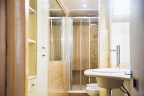 Ein modernes Badezimmer mit einer Duschkabine aus Glas, einem weißen Waschbecken und einer Toilette.