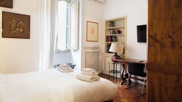 Ein Hotelzimmer mit Bett, Schreibtisch, Heizkörper und Bücherregal.