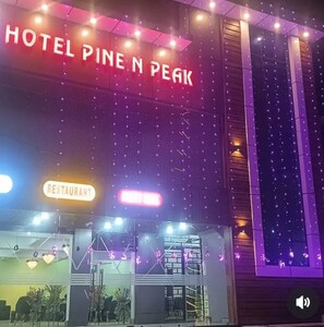 Un hotel chiamato "Pine N Peak", con un cartello ben visibile e un'insegna per il ristorante sottostante.