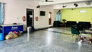 Eine großzügige Lobby mit Marmorboden, Deckenventilatoren und einer Sitzecke mit grünen Stühlen.