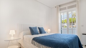 Un dormitorio con cama, dos lámparas de noche, una ventana con vistas y un radiador blanco.