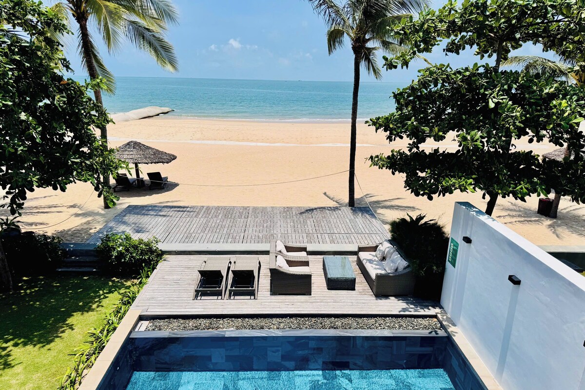 A pool area with a view of a beach and ocean.