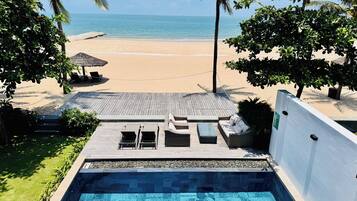 A pool area with a view of a beach and ocean.