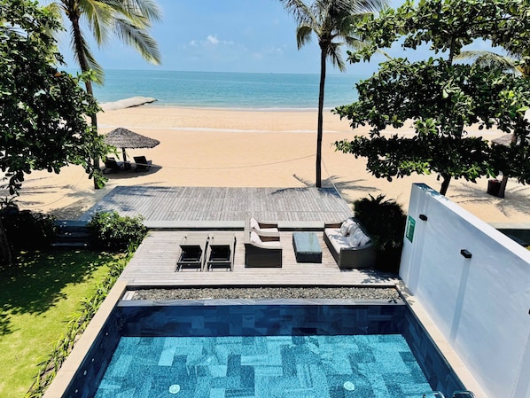 Un espace piscine offrant une vue sur une plage et l’océan.