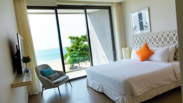 Camera d'albergo con un letto, una sedia, una TV e vista sulla spiaggia.