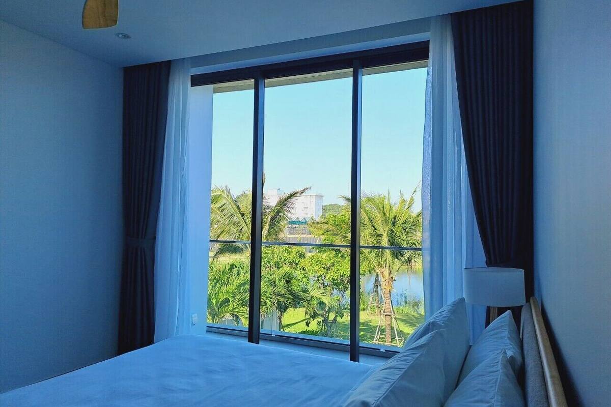 Una habitación de hotel con un ventanal grande, una cama y una mesita de noche.