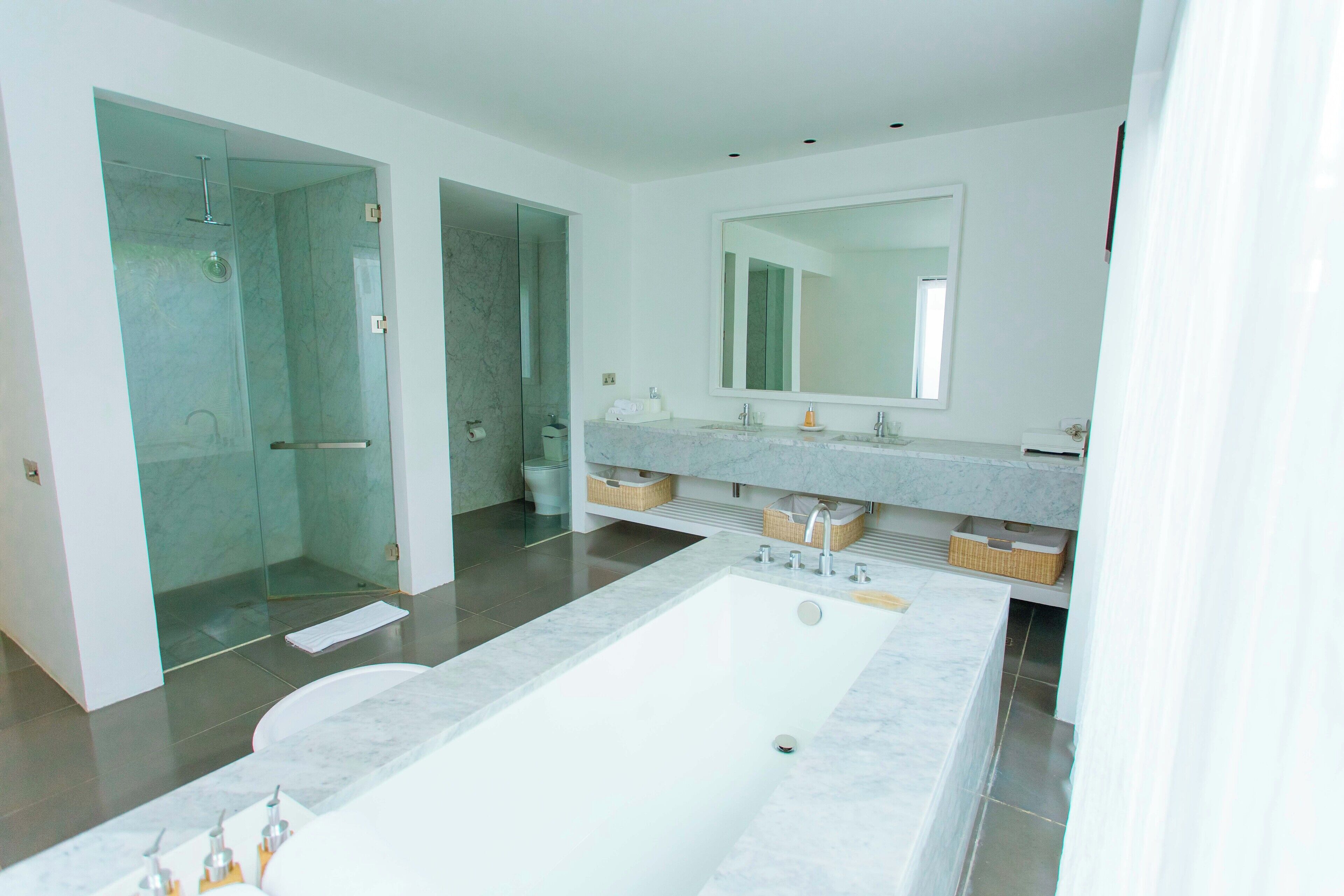 A modern bathroom with a large bathtub, a glass-enclosed shower, and a vanity with a large mirror.