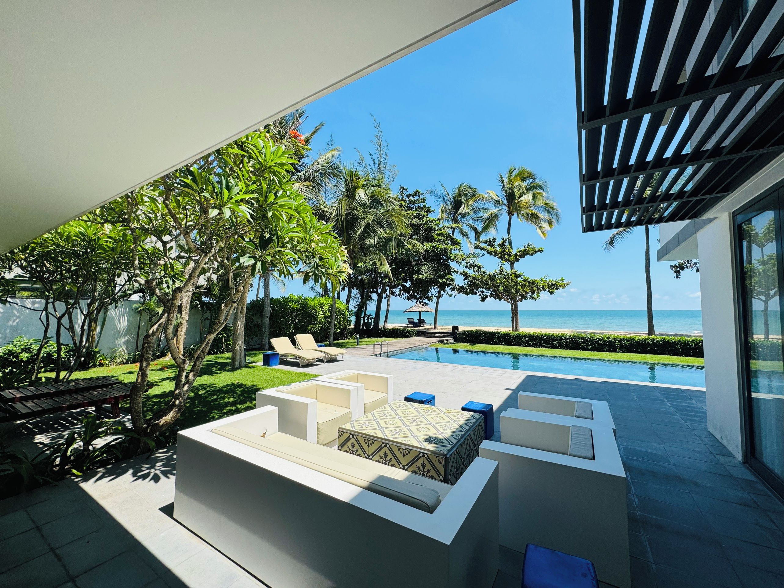 A modern outdoor lounge area with a pool, seating, and a view of the ocean.