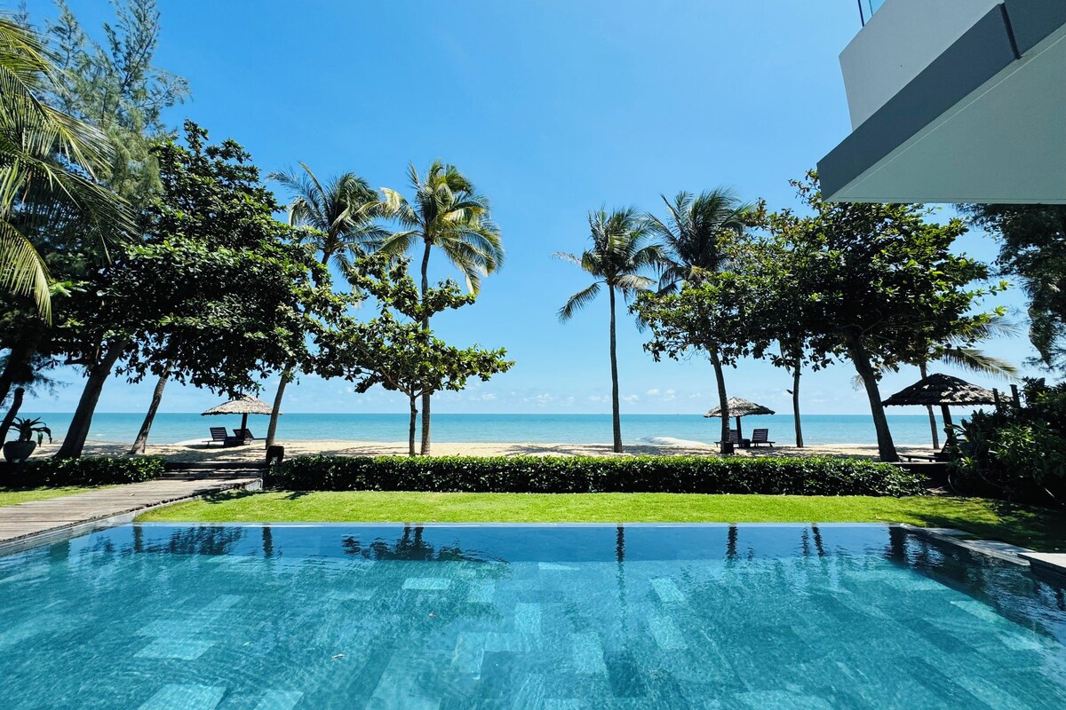 A pool with a clear view of the ocean and palm trees.