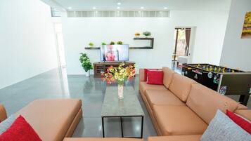 A modern living room with a sofa, coffee table, TV, and a foosball table.