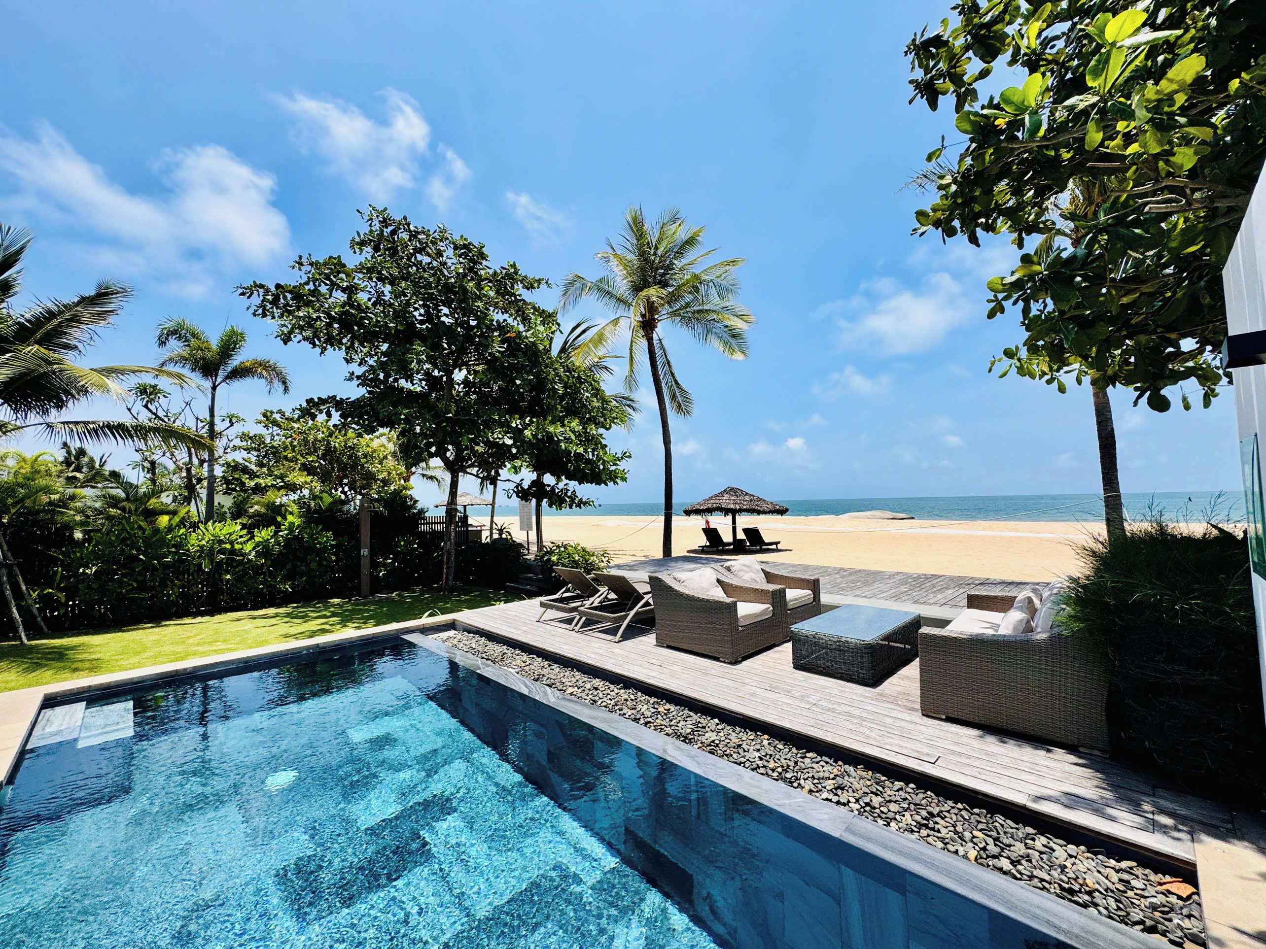 A pool area with lounge chairs and a view of the beach.